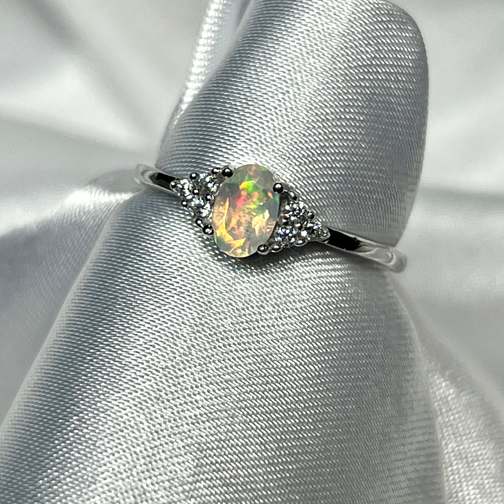 An elegant Ethiopian Opal Ring with Cubic Zirconia Stones on a white cloth.