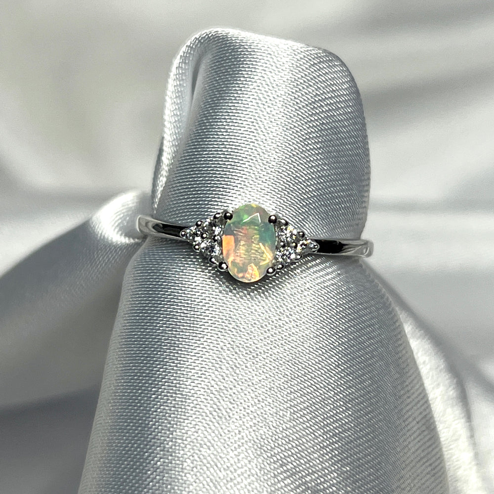 
                  
                    An elegant Ethiopian Opal Ring with Cubic Zirconia Stones on a white cloth.
                  
                