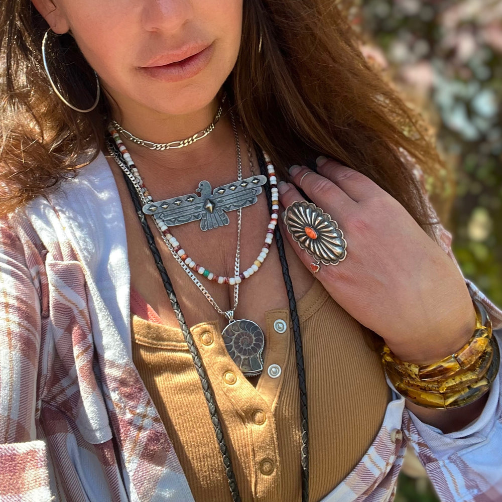 
                  
                    A woman in a plaid shirt wearing a necklace adorned with striking Super Silver Nautilus pendants, creating a bold look.
                  
                