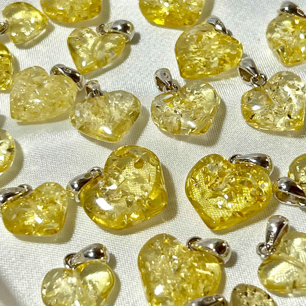 
                  
                    A group of Super Silver Charming Baltic Amber Heart Pendants on a white cloth.
                  
                