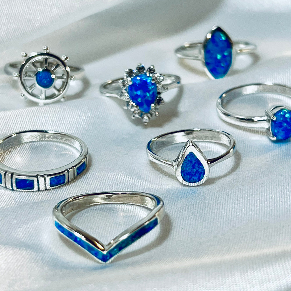 
                  
                    An assortment of sterling silver rings with Stackable Bands with Square Lab Opals displayed on a draped white fabric.
                  
                