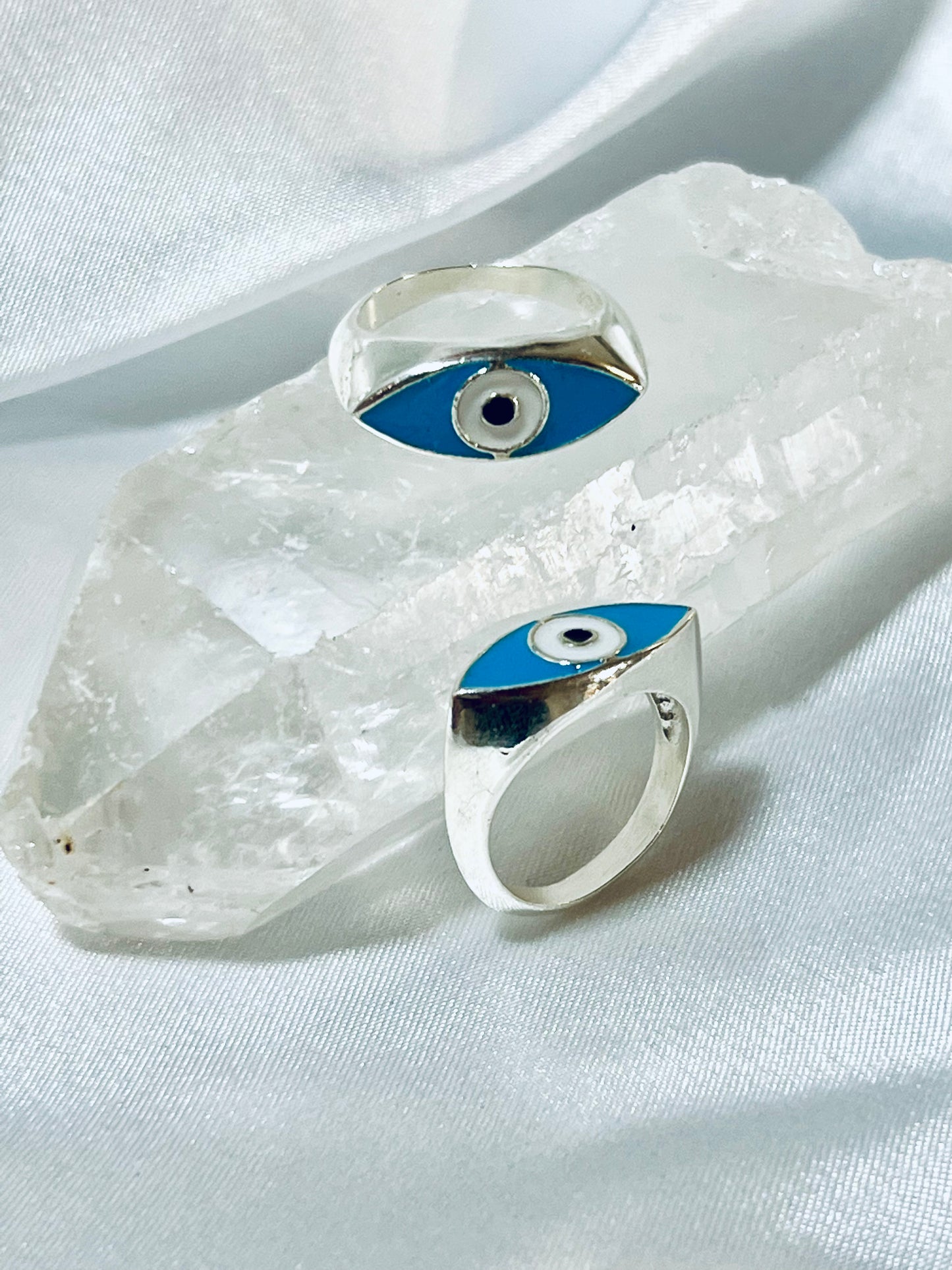 Two Super Silver Evil Eye Rings on top of a crystal.