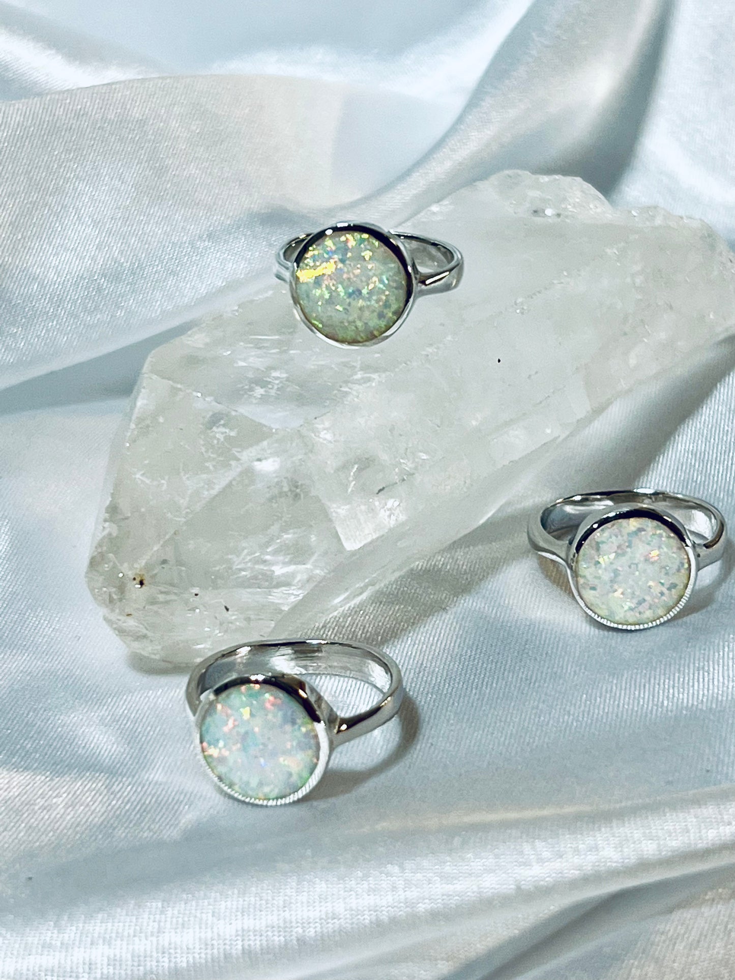 Three Simple Round Opal Rings, by Super Silver, elegantly placed on top of a shimmering crystal.