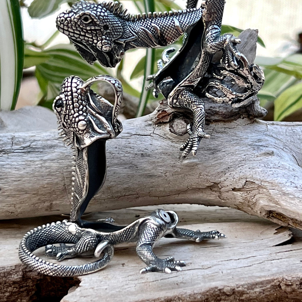 
                  
                    A pair of handcrafted Super Silver Iguana Pendants sitting on a piece of wood.
                  
                