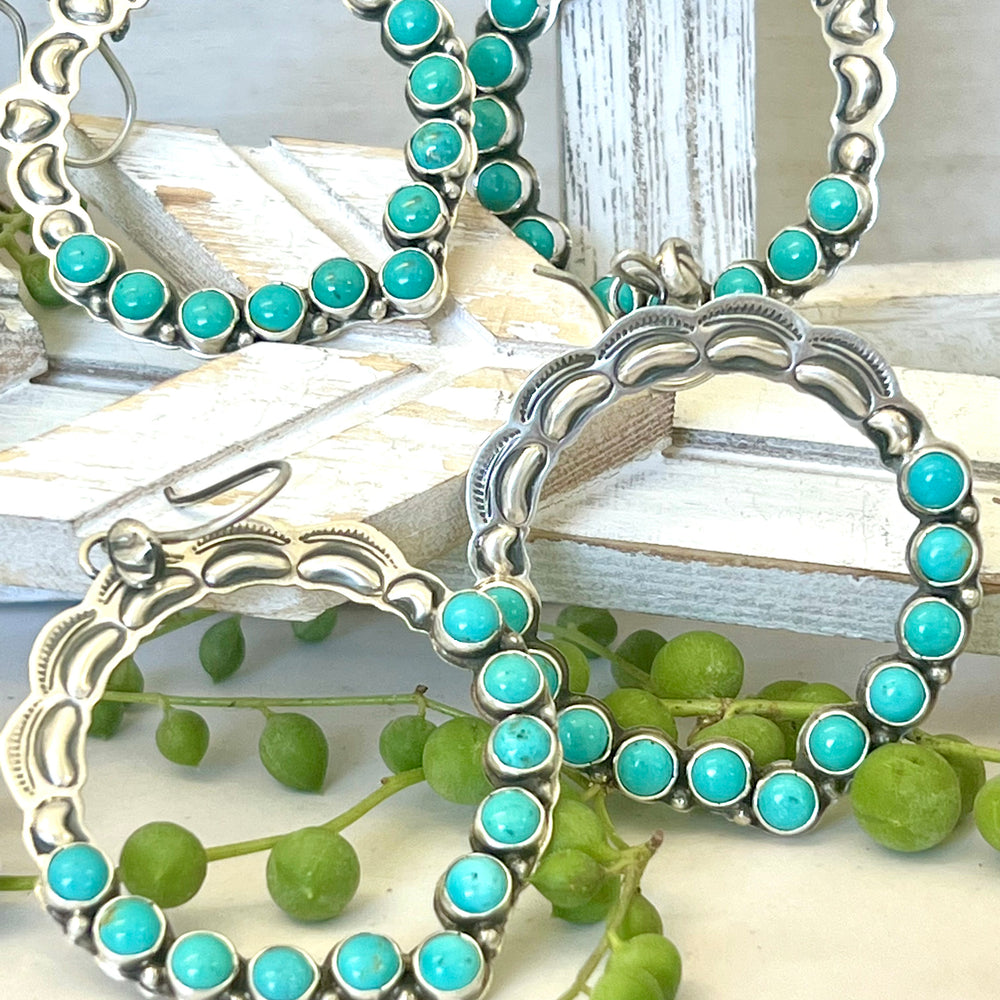 
                  
                    Four Super Silver Statement Handmade Turquoise Earrings exude southwestern elegance on a wooden table.
                  
                