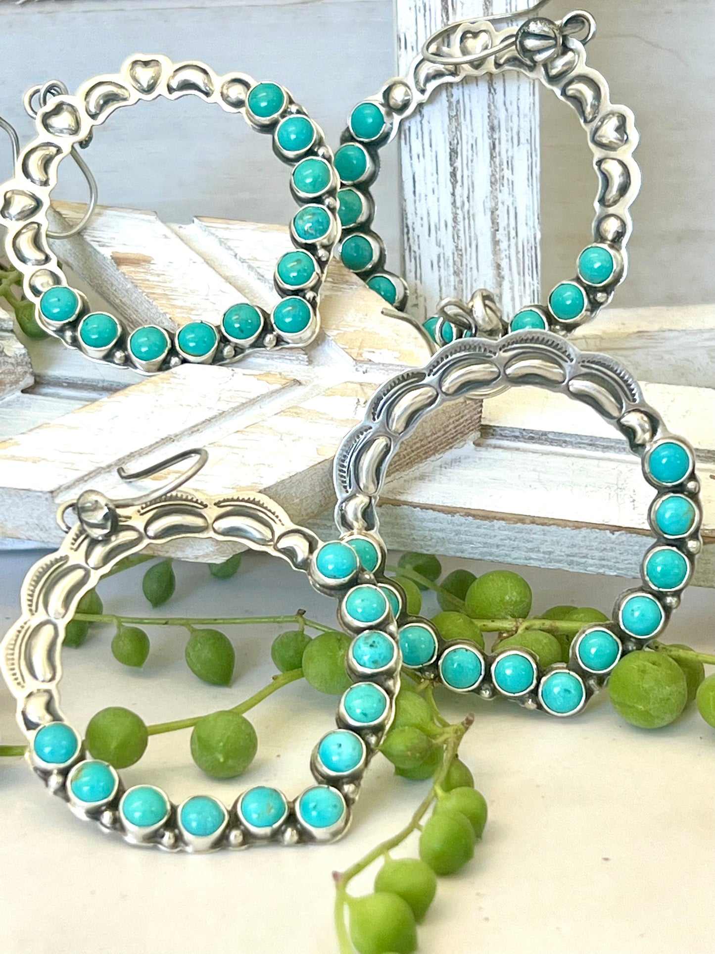 
                  
                    Four Super Silver Statement Handmade Turquoise Earrings exude southwestern elegance on a wooden table.
                  
                