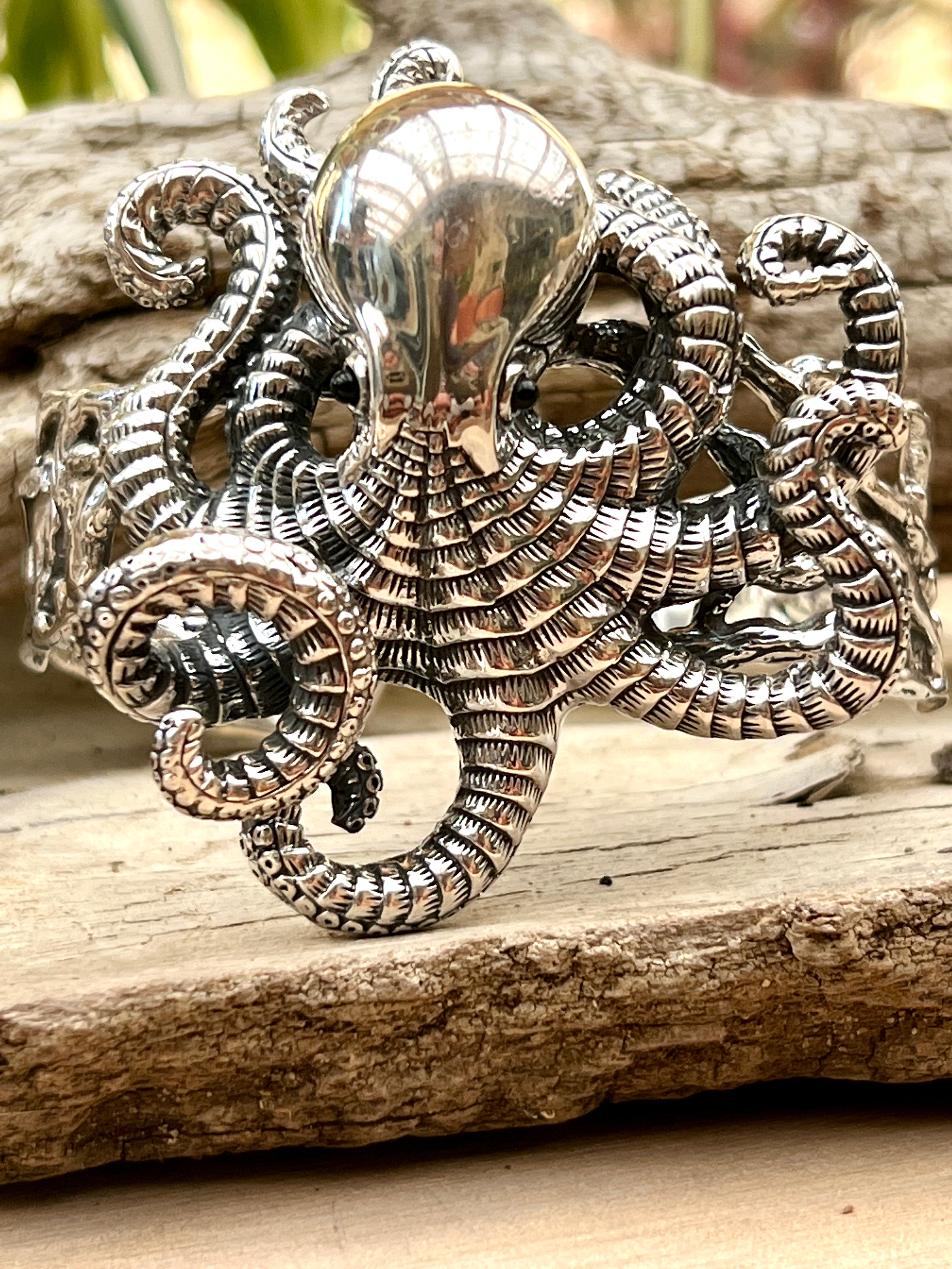 A Super Silver Octopus Statement Bracelet adorned on a piece of wood.