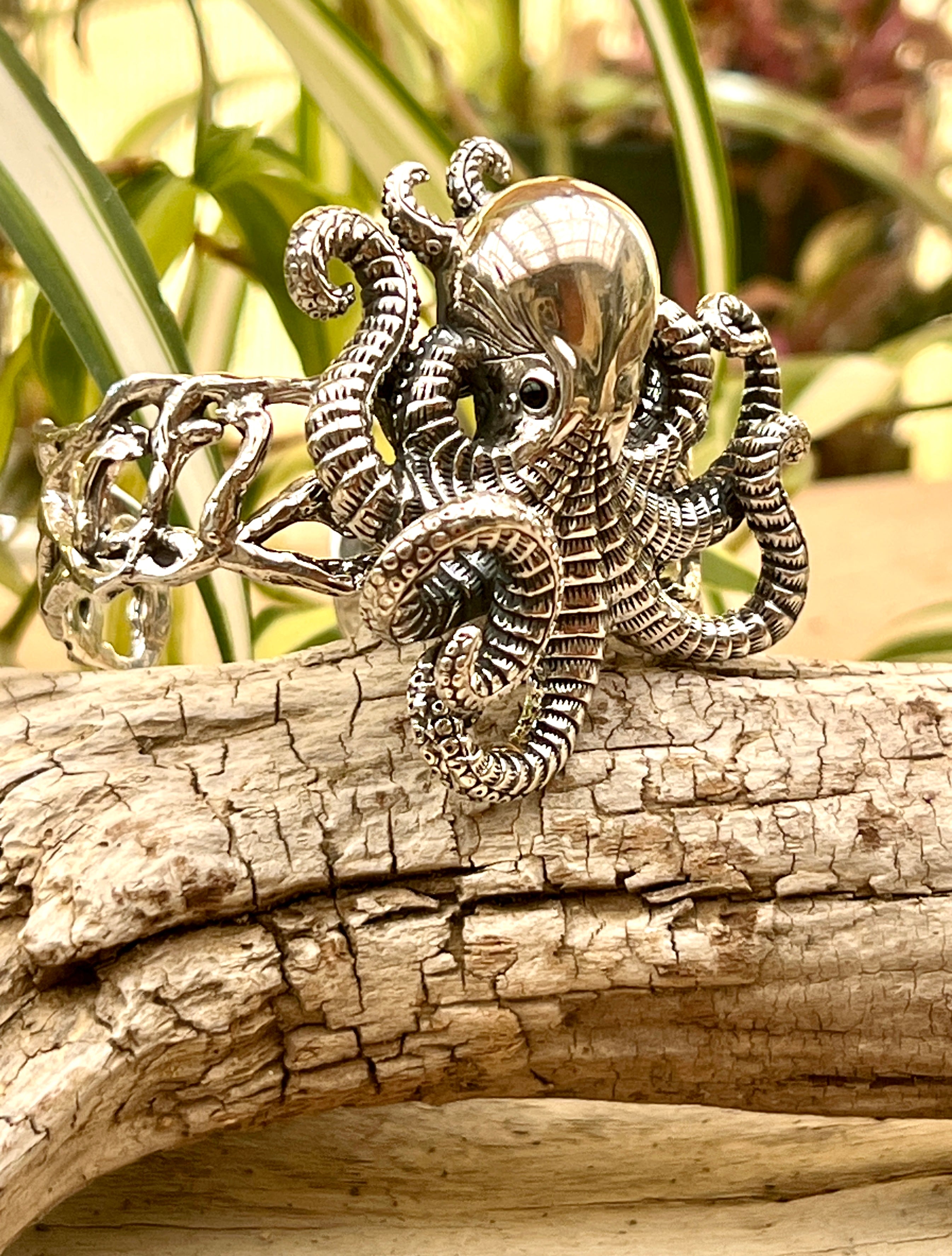 A Super Silver Octopus Statement Bracelet sitting on a piece of wood.
