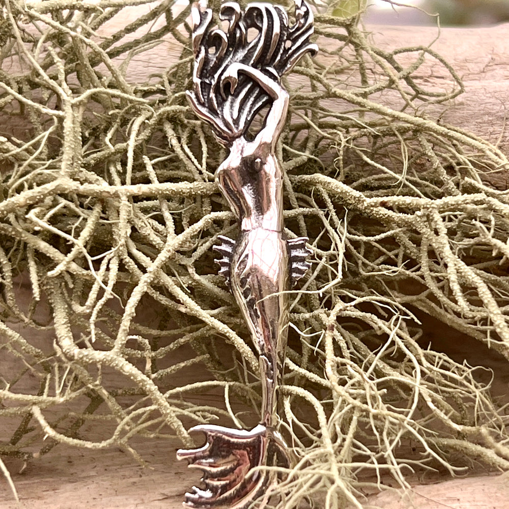 
                  
                    An Enticing Mermaid Pendant by Super Silver is sitting on top of some twigs.
                  
                
