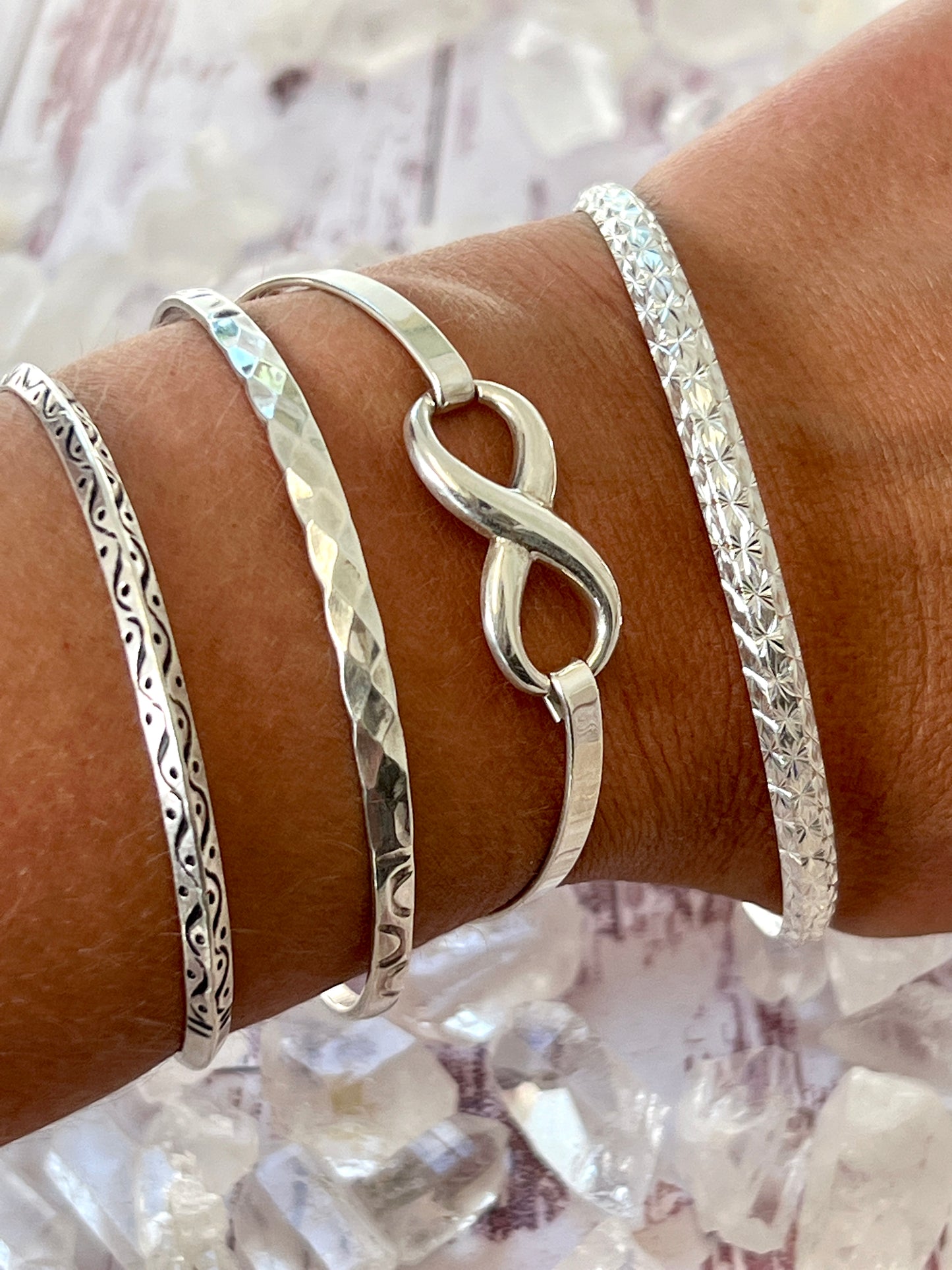 
                  
                    Three stunning Super Silver Elegant Etched Bangle Bracelets on a woman's wrist.
                  
                