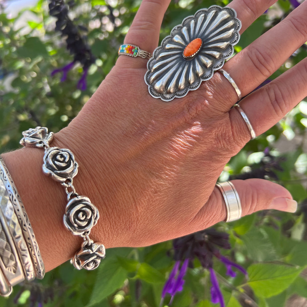 
                  
                    A woman's hand is holding a Super Silver Chic Link Rose Bracelet adorned with a delicate rose design, creating a stunning statement piece.
                  
                