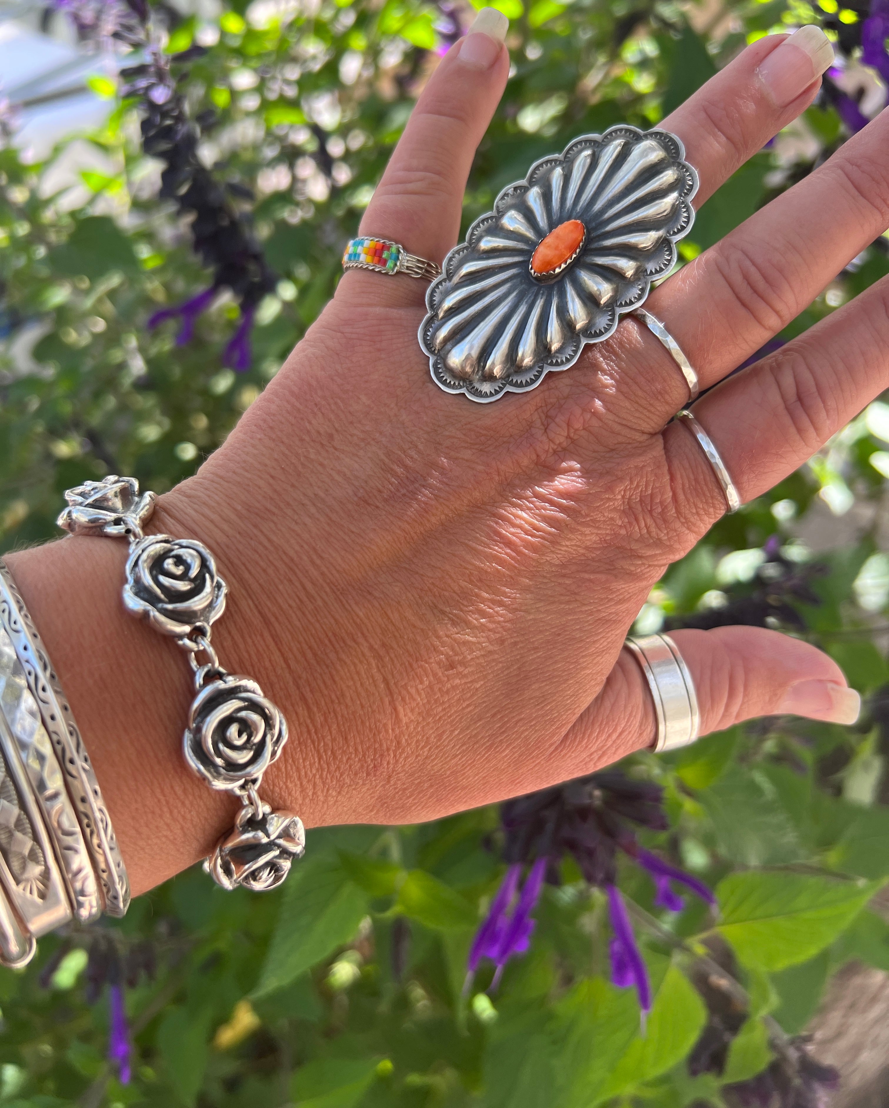 A woman's hand is holding a Super Silver Chic Link Rose Bracelet adorned with a delicate rose design, creating a stunning statement piece.