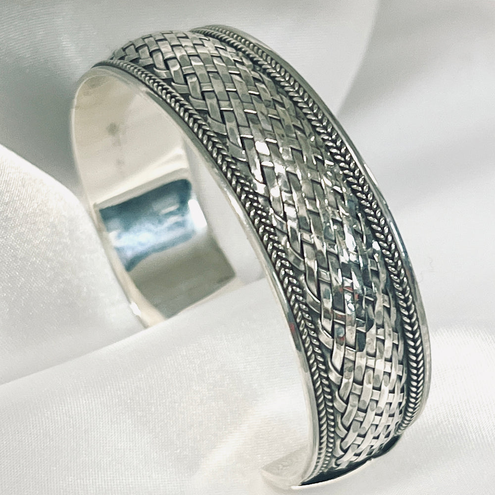 
                  
                    A Super Silver Woven Silver cuff bracelet with an oxidized basket weave design, displayed on a white cloth.
                  
                