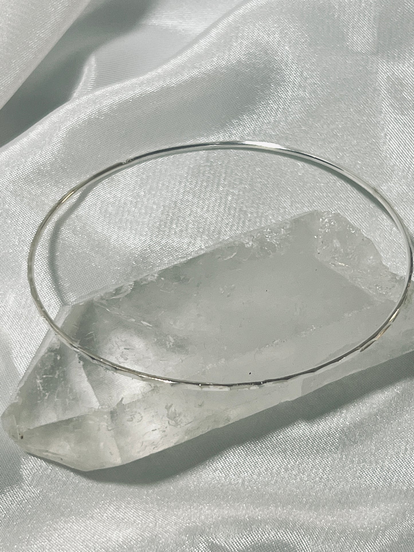 
                  
                    A Squared Faceted Bangle Bracelet adorned with facets, sitting atop a crystal from Super Silver.
                  
                