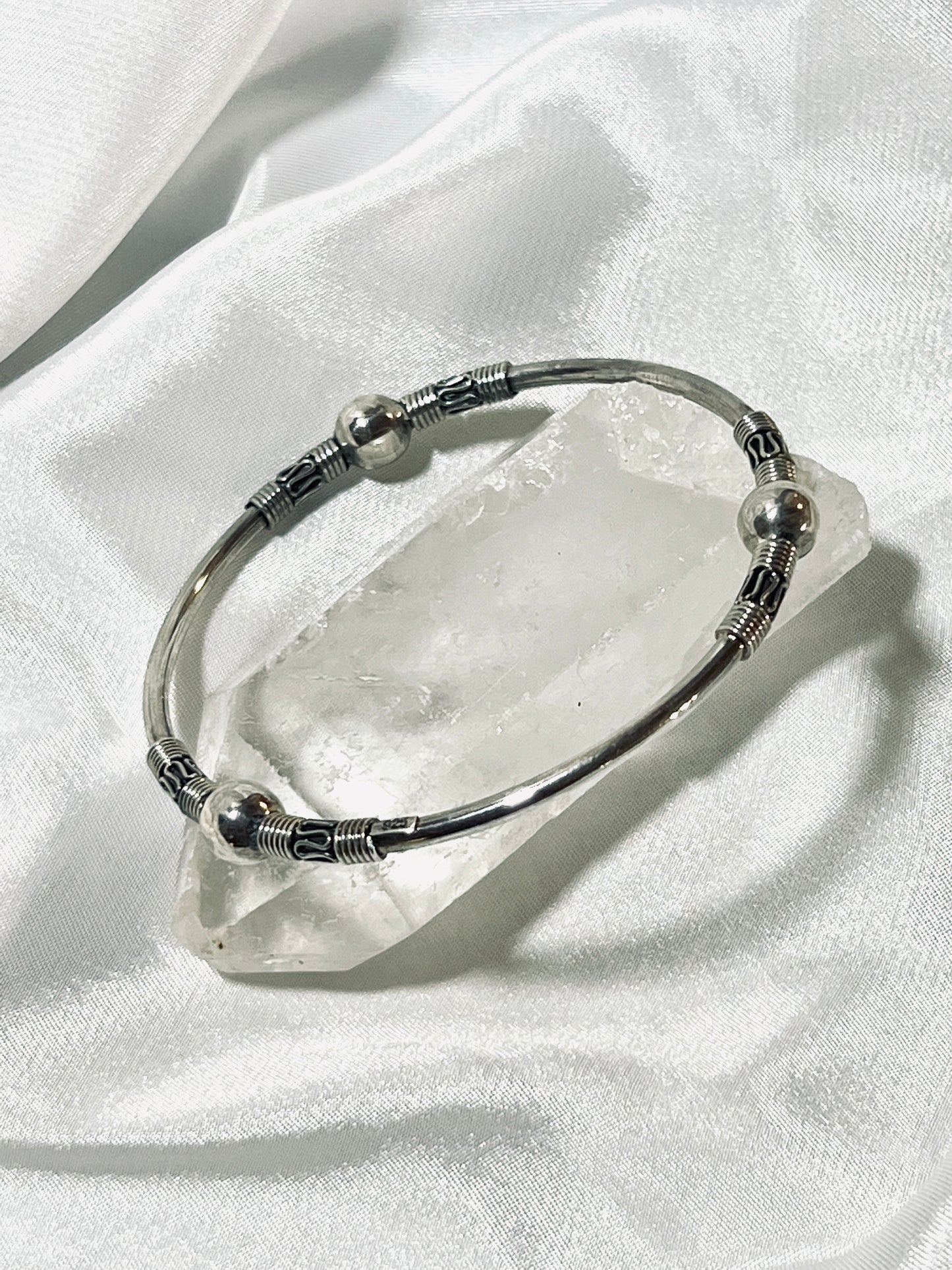 
                  
                    A Super Silver Bali Style Bangle Bracelet resting on a crystal, exuding an earthy boho vibe.
                  
                