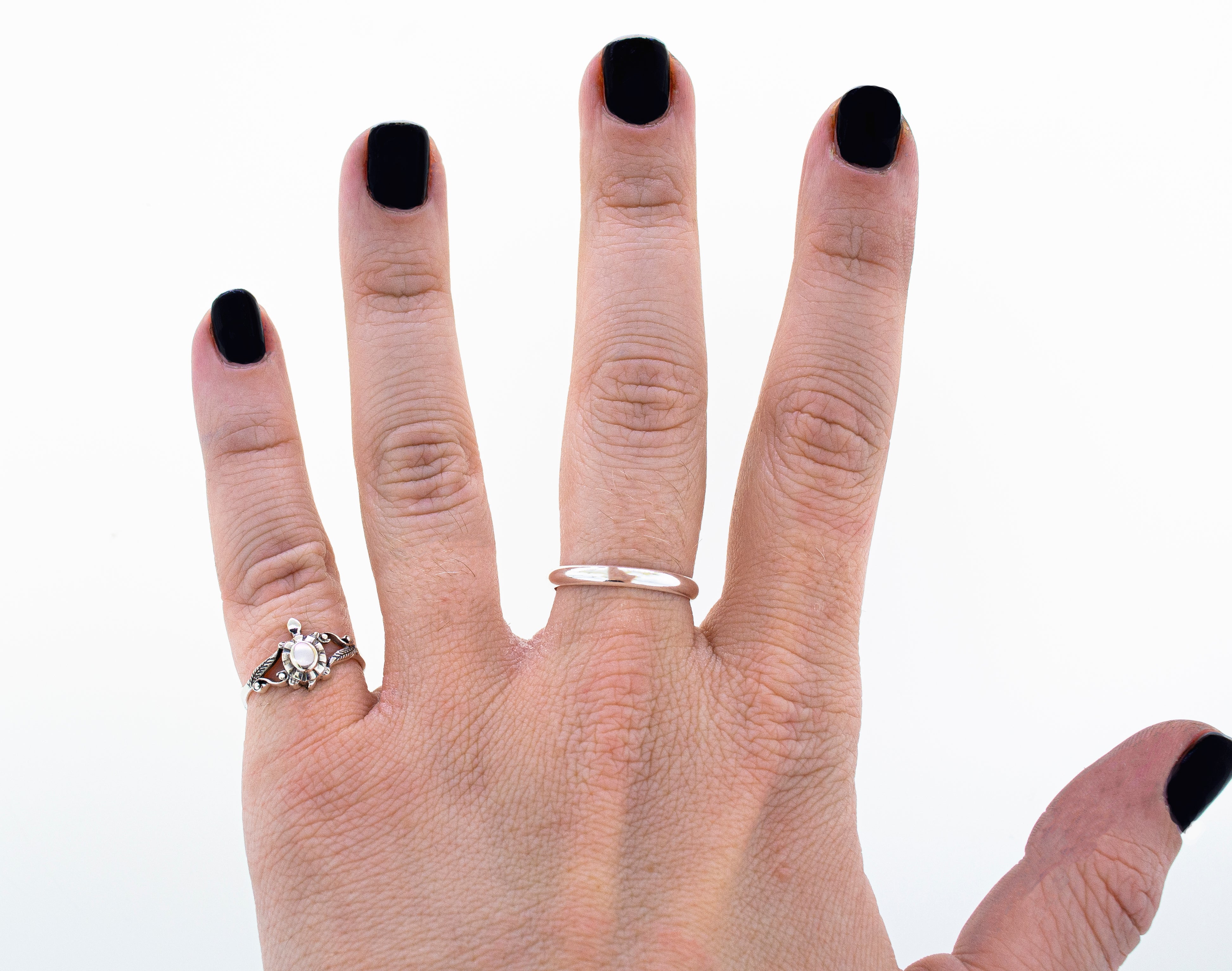 A woman's hand adorned with an Inlay Stone Turtle Ring with Leaf Detailing.