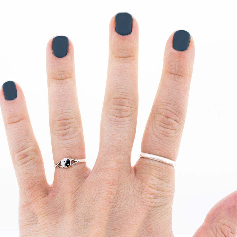 
                  
                    A woman's hand with black nails adorned with a Super Silver Delicate Yin Yang Ring.
                  
                