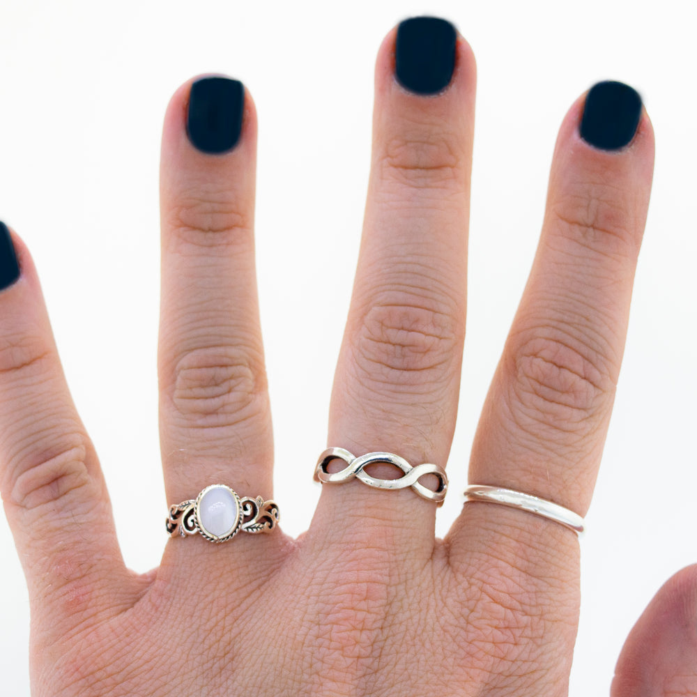 
                  
                    A woman's hand with an Oval Inlaid Ring with Swirls and Leaf Detailing.
                  
                