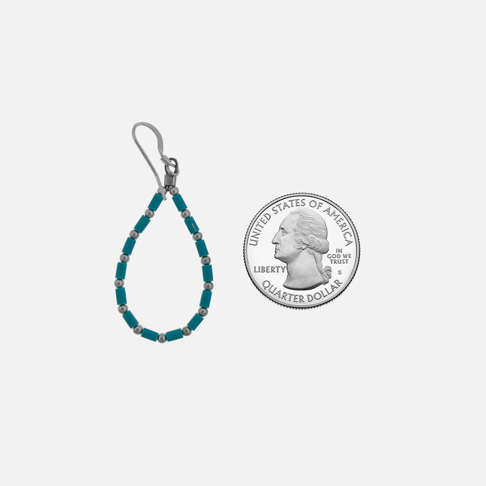 A Super Silver silver coin nestled beside a Native American Silver and Turquoise Beaded Drop Earrings.