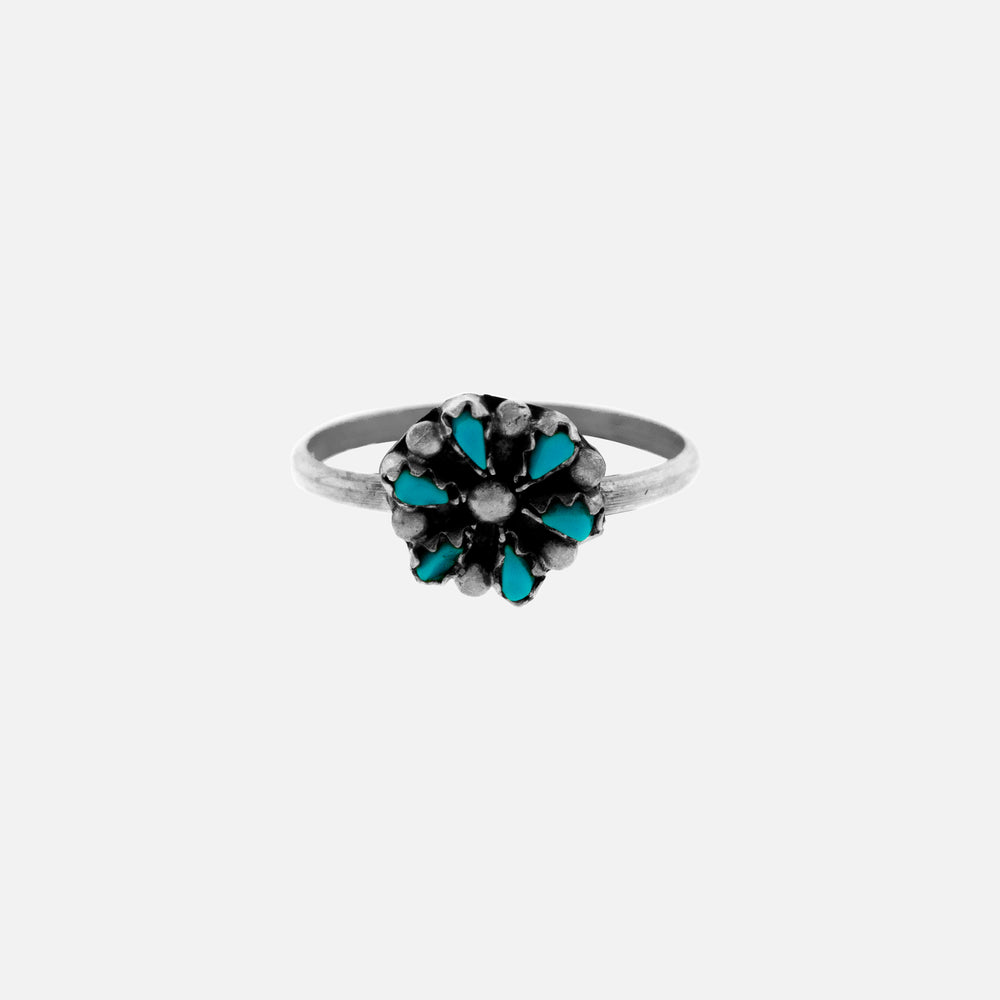 A sterling silver ring with Small Native American Turquoise Flower stones on a native inspired white background.