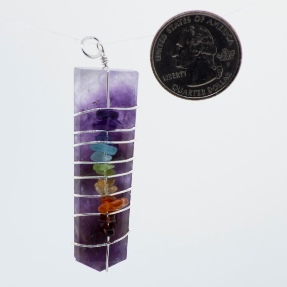 A Super Silver Wire Wrapped Tapered Slab With Chakra Stones pendant adorned with a coin.