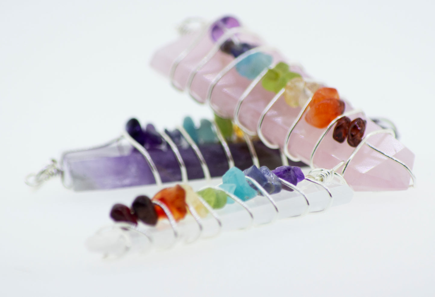
                  
                    A group of Super Silver Wire Wrapped Tapered Slabs With Chakra Stones, each beautifully adorned with a different colored gemstone, delicately strung together on a wire with Silver Plated accents.
                  
                