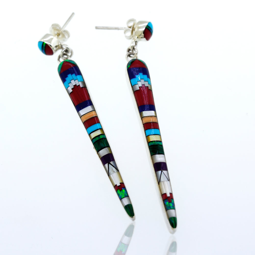 A pair of Super Silver Beautiful Designer Multi-Stone Elongated Teardrop Earrings with colorful inlaid details, crafted from sterling silver, resting on a white surface.