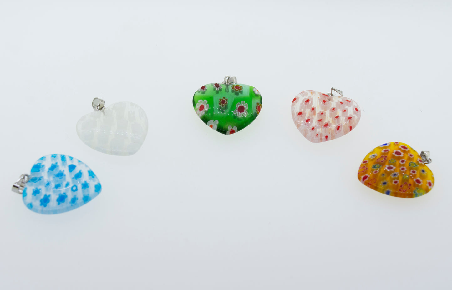 
                  
                    A group of Super Silver translucent resin heart pendants adorned with vibrant flower patterns, showcasing a variety of captivating color schemes, resting on a pristine white surface.
                  
                