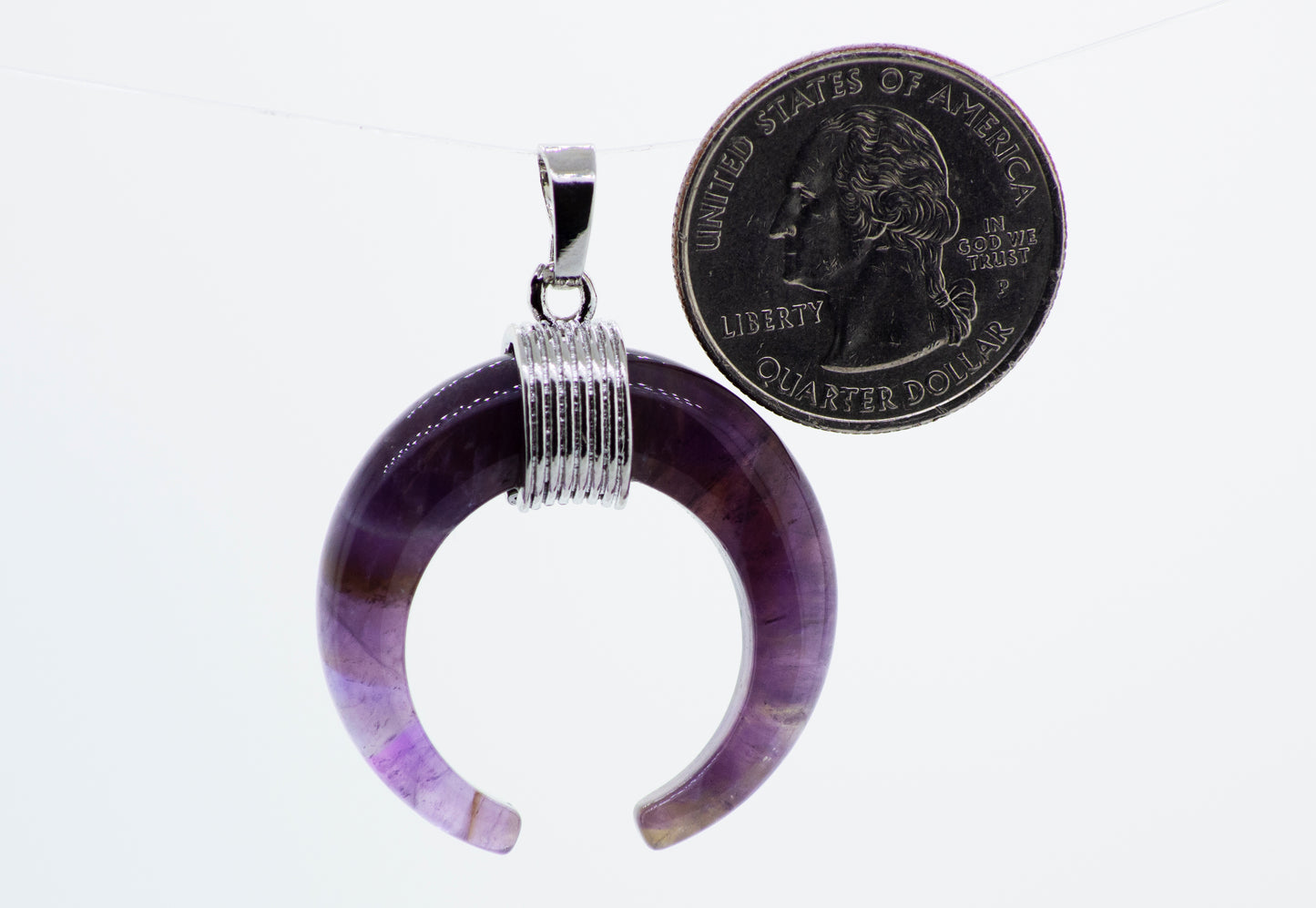A Super Silver wire pattern setting holds a purple Naja Stone pendant with a coin hanging from it.