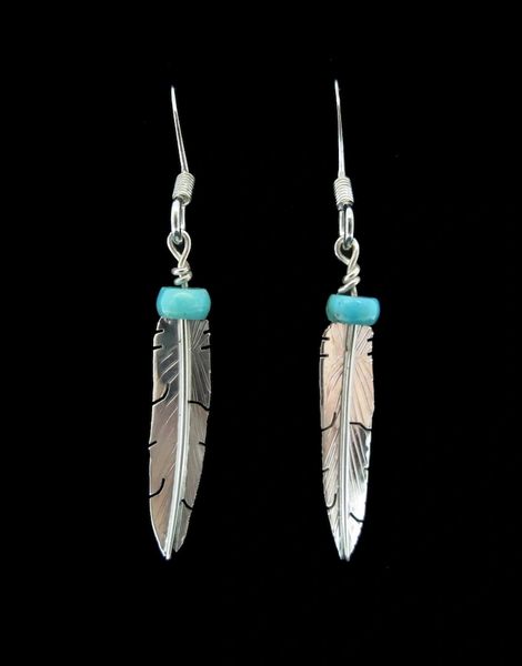 A pair of Super Silver Turquoise Feather Dangle Earrings adorned with vibrant turquoise beads.