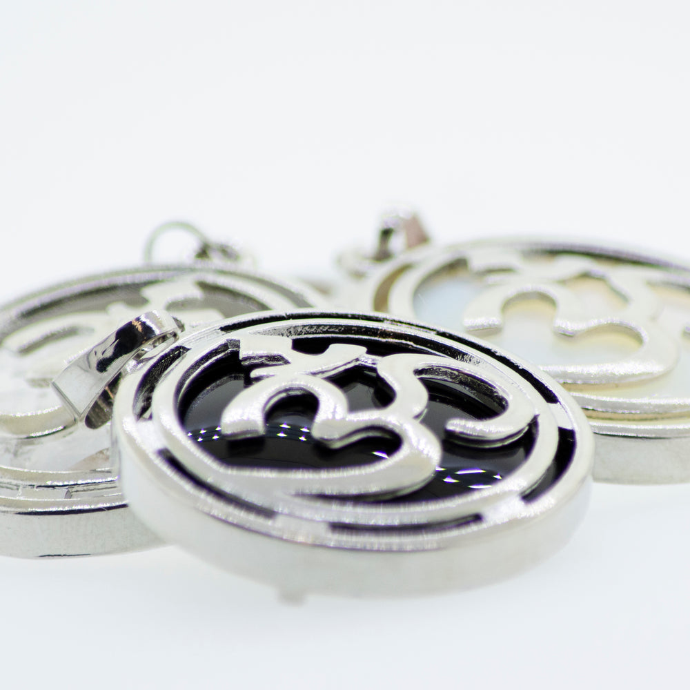 Three Super Silver Om Pendants on a white surface.