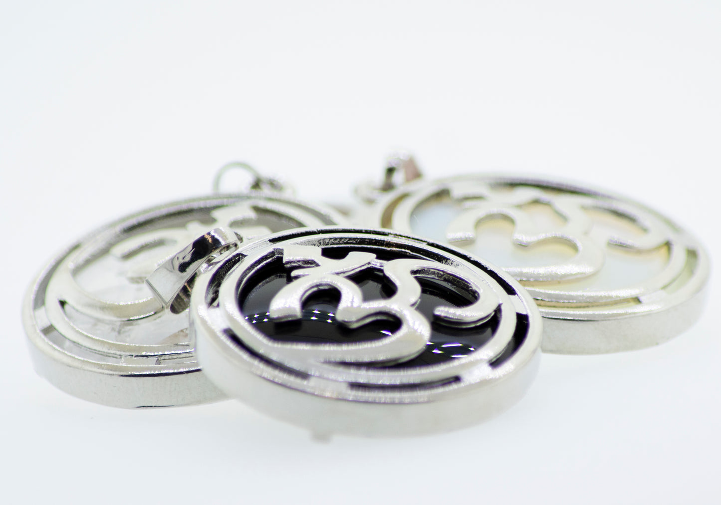
                  
                    Three Super Silver Om Pendants on a white surface.
                  
                