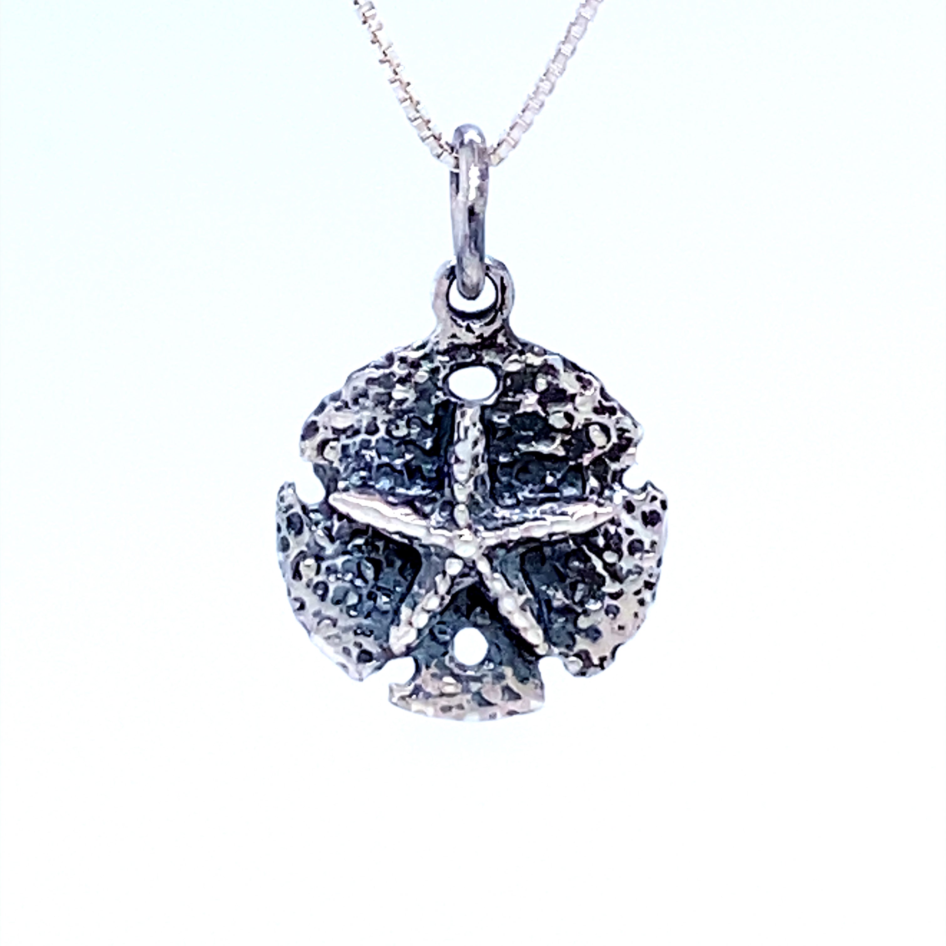 A Small Oxidized Sand Dollar Charm from Super Silver on a chain, perfect for beach lovers.