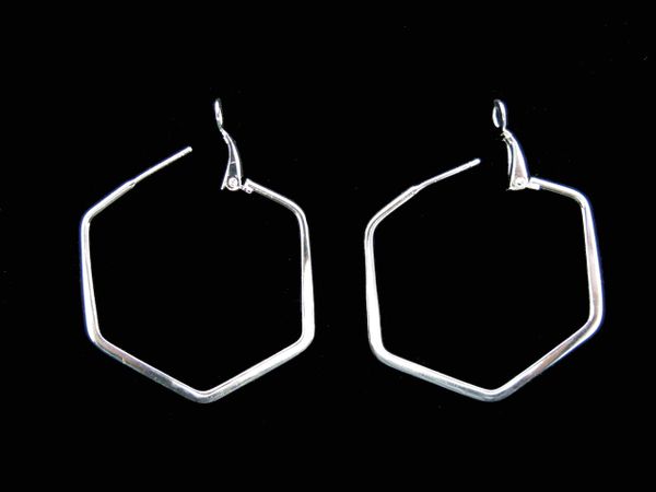A pair of Super Silver Hexagon Medium Hoop Earrings on a black background.