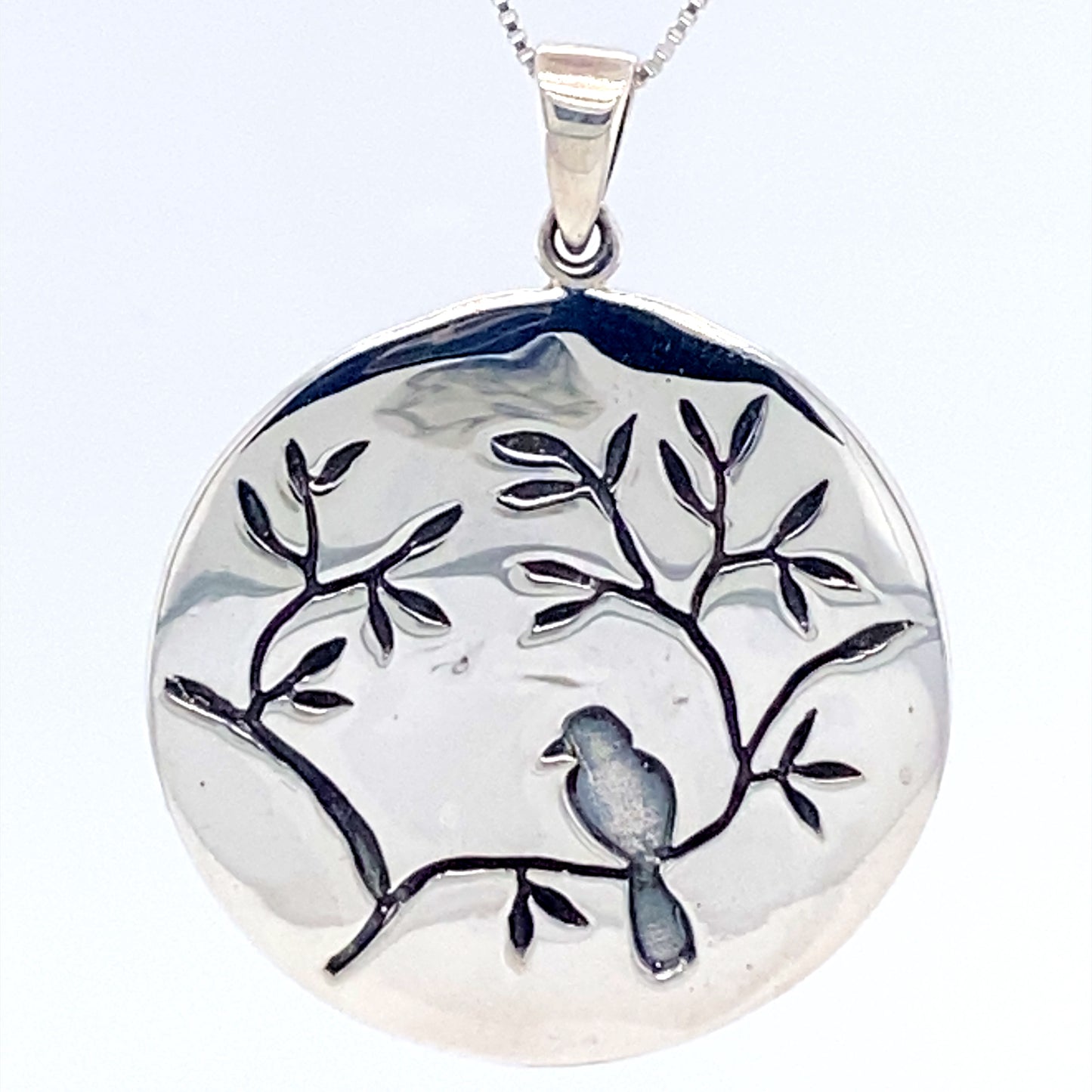 A Large Circle Nature Pendant with Bird featuring a bird perched on a branch by Super Silver.