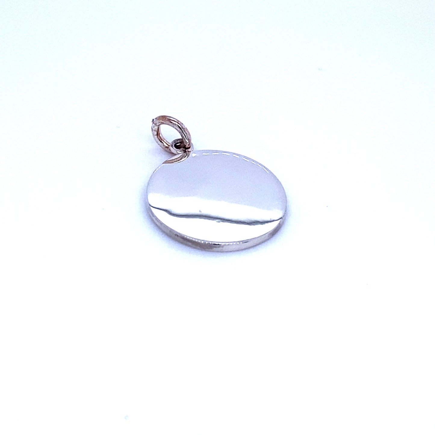 
                  
                    A small, Simple Round Engravable Pendant in sterling silver by Super Silver resting on a white surface.
                  
                