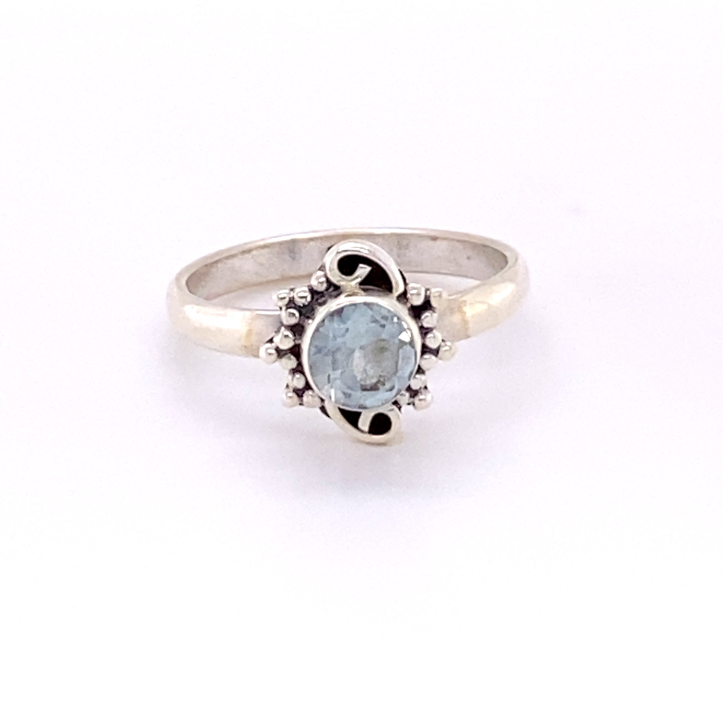 A Small Round Gemstone Ring with Bead and Swirl Border with a blue topaz stone.