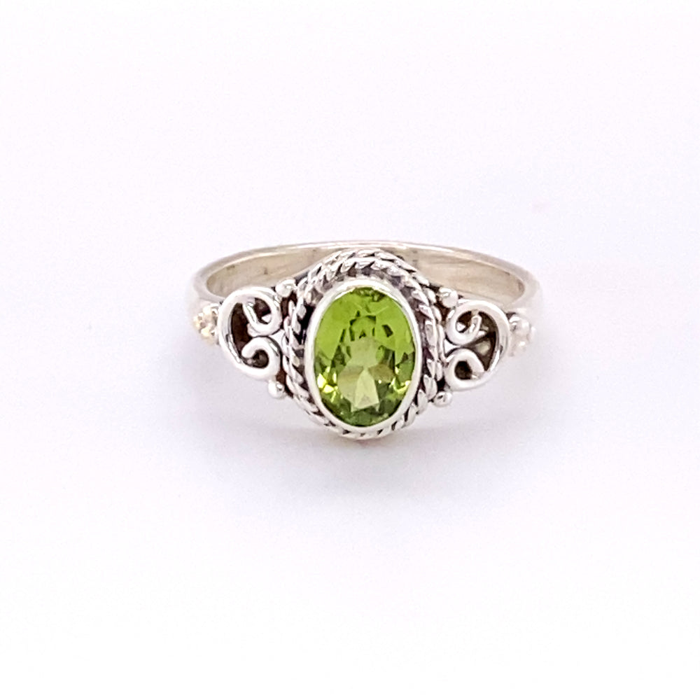 This Super Silver Oval Peridot Ring with Rope and Swirl Border showcases a stunning peridot surrounded by sparkling diamonds.