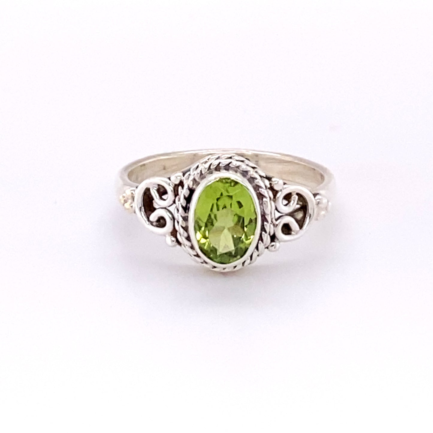 This Super Silver Oval Peridot Ring with Rope and Swirl Border showcases a stunning peridot surrounded by sparkling diamonds.