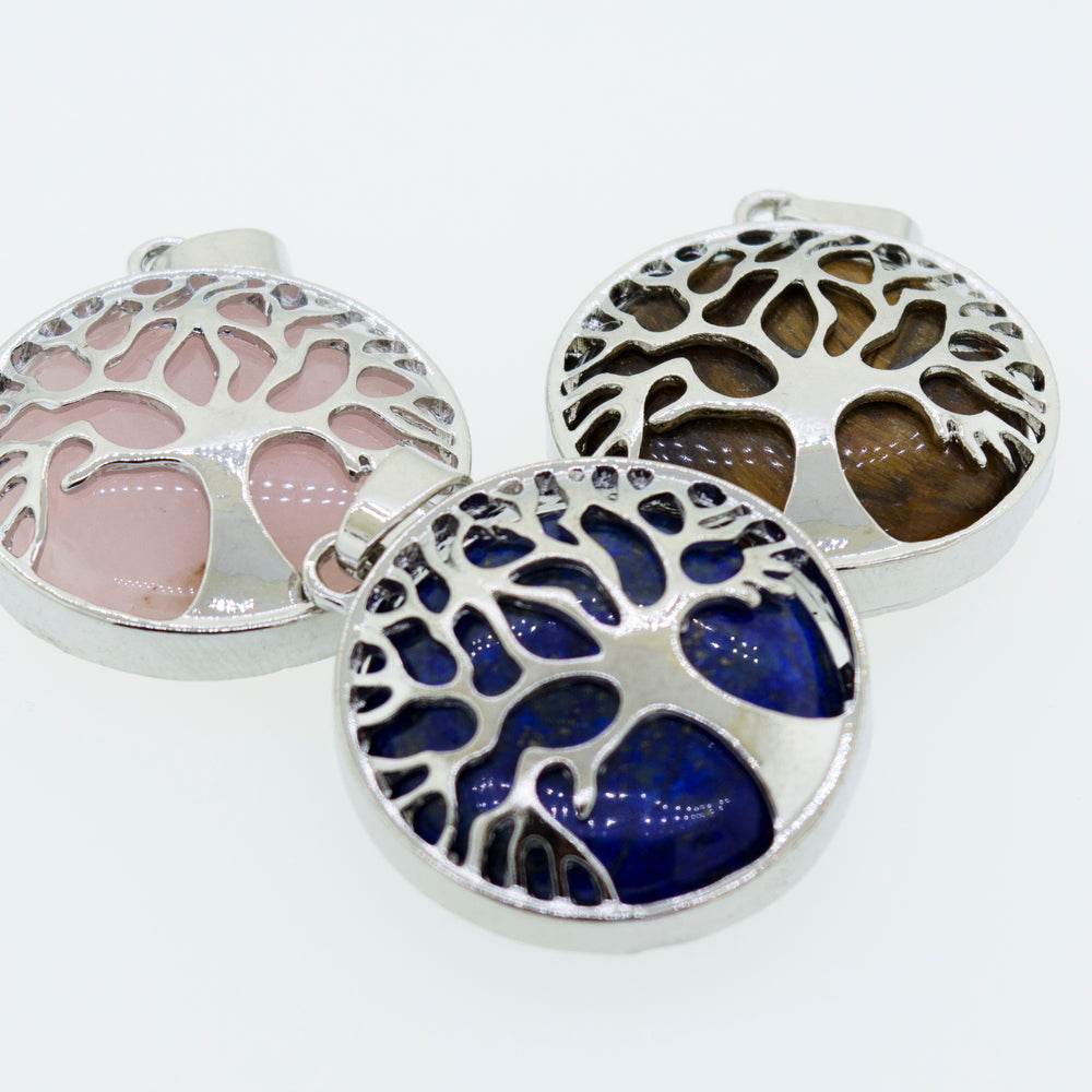 
                  
                    Three beautiful Super Silver Tree of Life pendants on a white surface.
                  
                