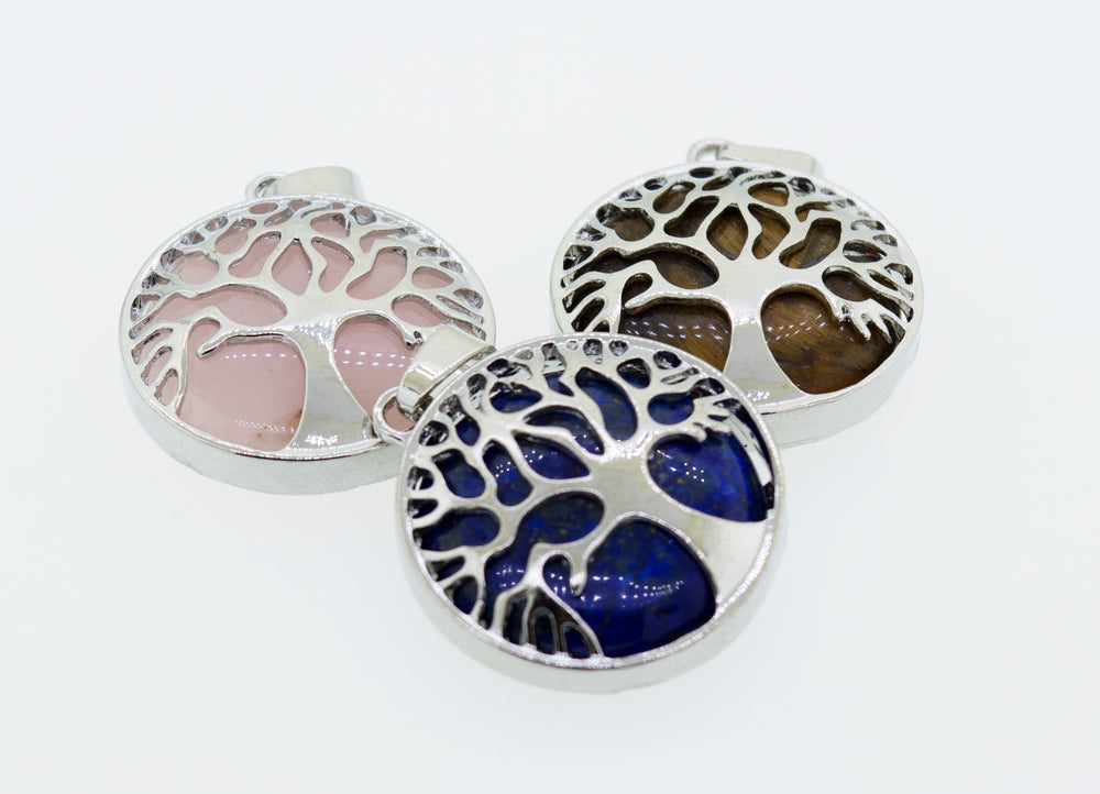 Three beautiful Super Silver Tree of Life pendants on a white surface.