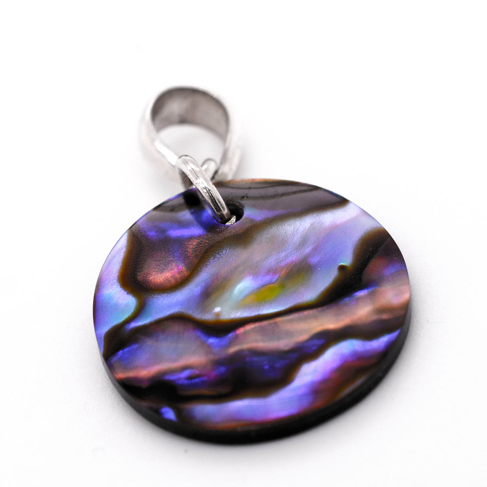 A handmade Super Silver Charming Abalone Pendant showcasing its healing properties, placed delicately on a pristine white surface.