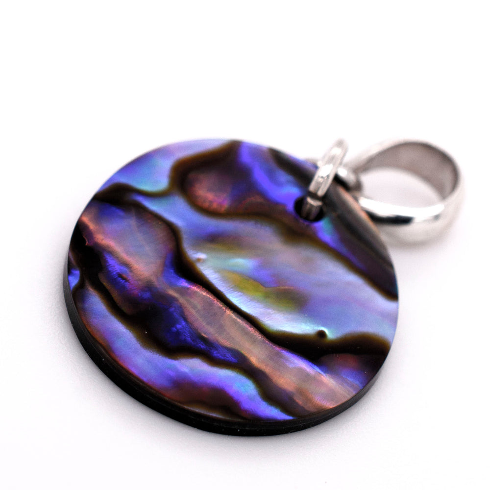 A Super Silver Charming Abalone Pendant displayed on a white surface, showcasing its exquisite beauty and healing properties.