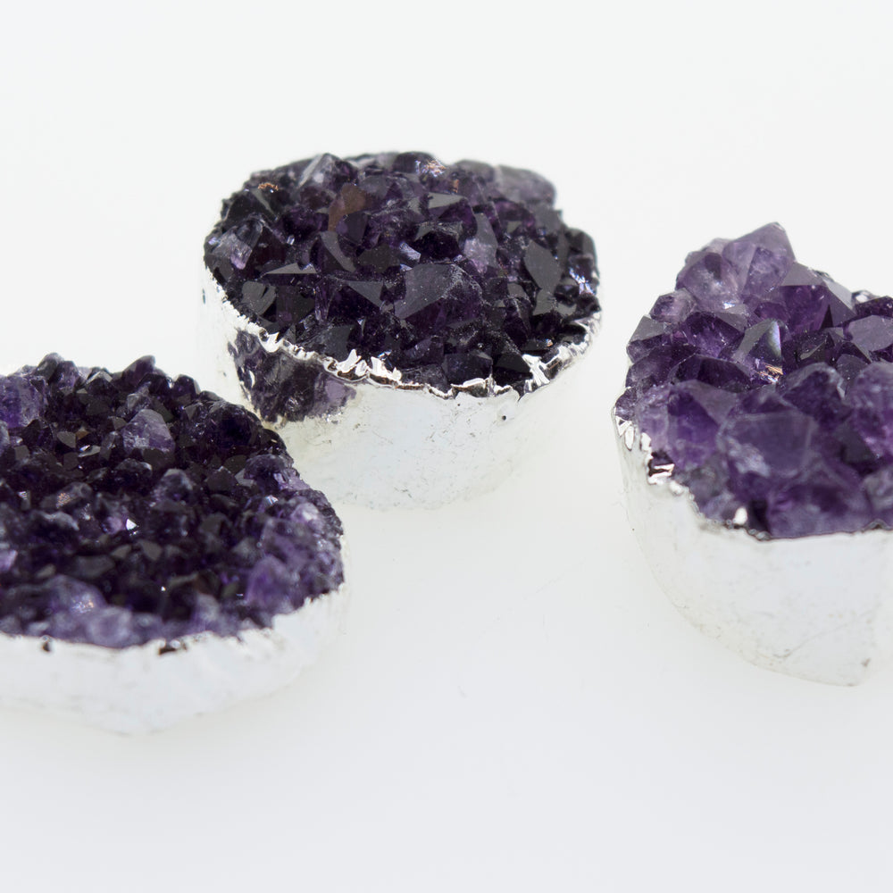 
                  
                    Three Super Silver Amethyst Geode Pendants on a white surface with a pendant accent.
                  
                
