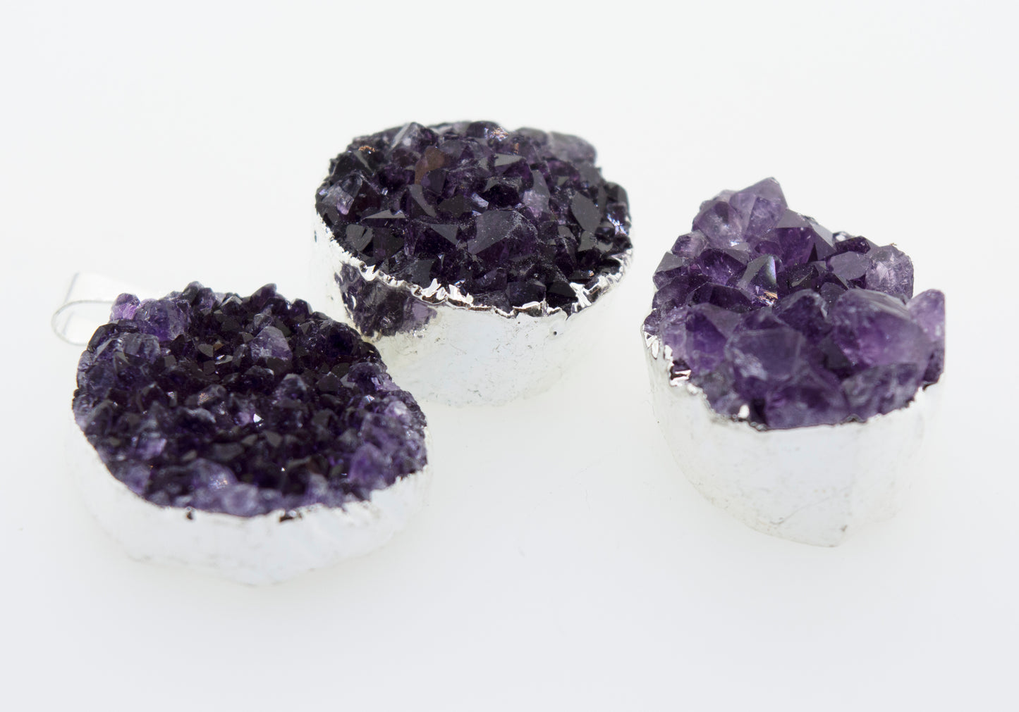 
                  
                    Three Super Silver Amethyst Geode Pendants on a white surface with a pendant accent.
                  
                