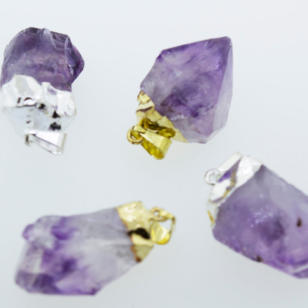 Purple natural amethyst crystals on a white surface enhanced by a Super Silver gold plated setting.