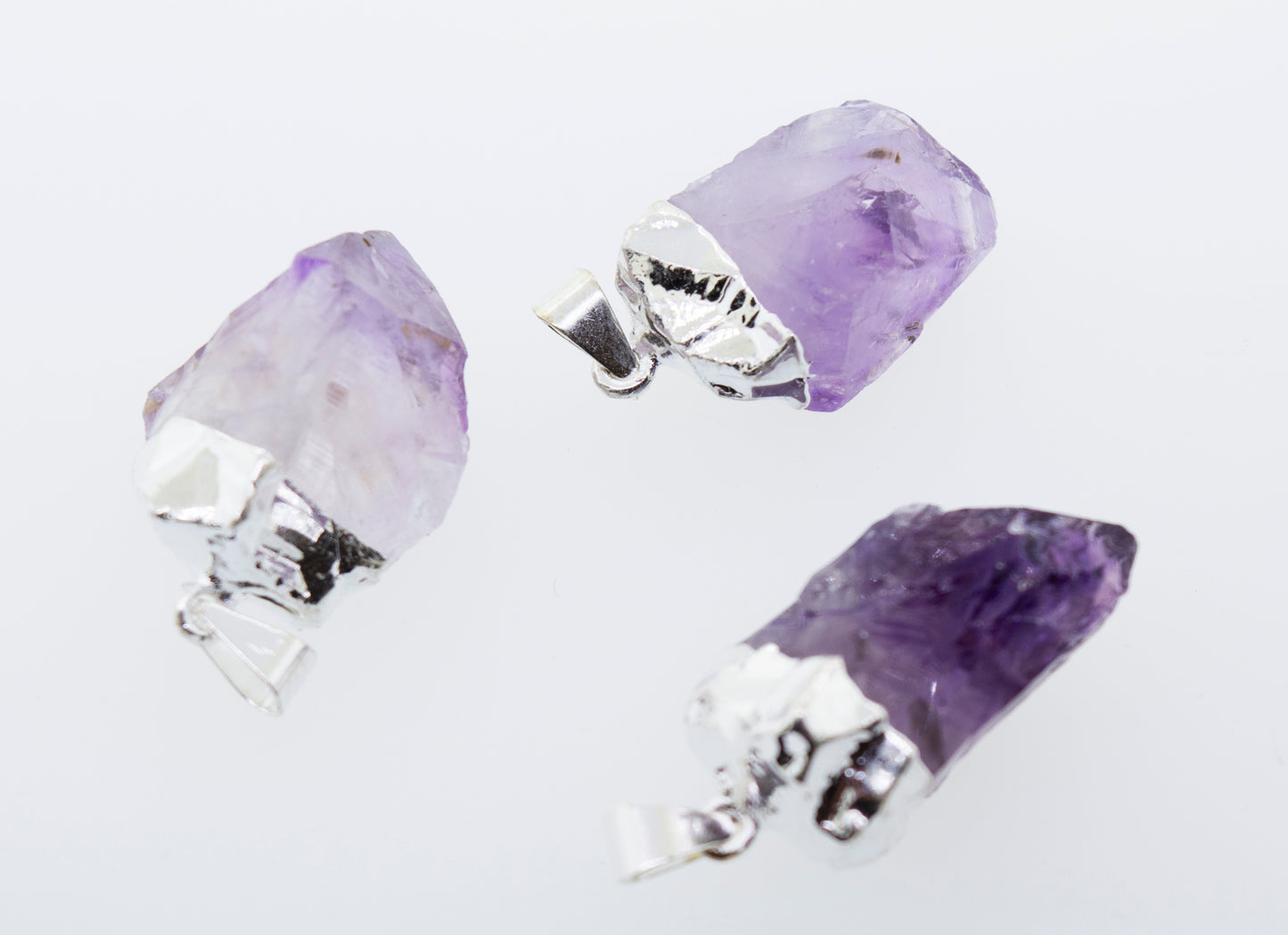 
                  
                    Three Natural Amethyst Crystal Pendants on a Super Silver plated surface.
                  
                