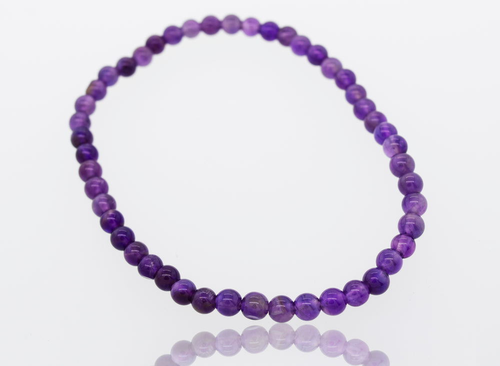 A Small Stone Beads Bracelet, featuring six different gemstones, held together by an elastic polyester cord. The vibrant purple amethyst beads glisten on a crisp white surface. (Brand Name: Super Silver)