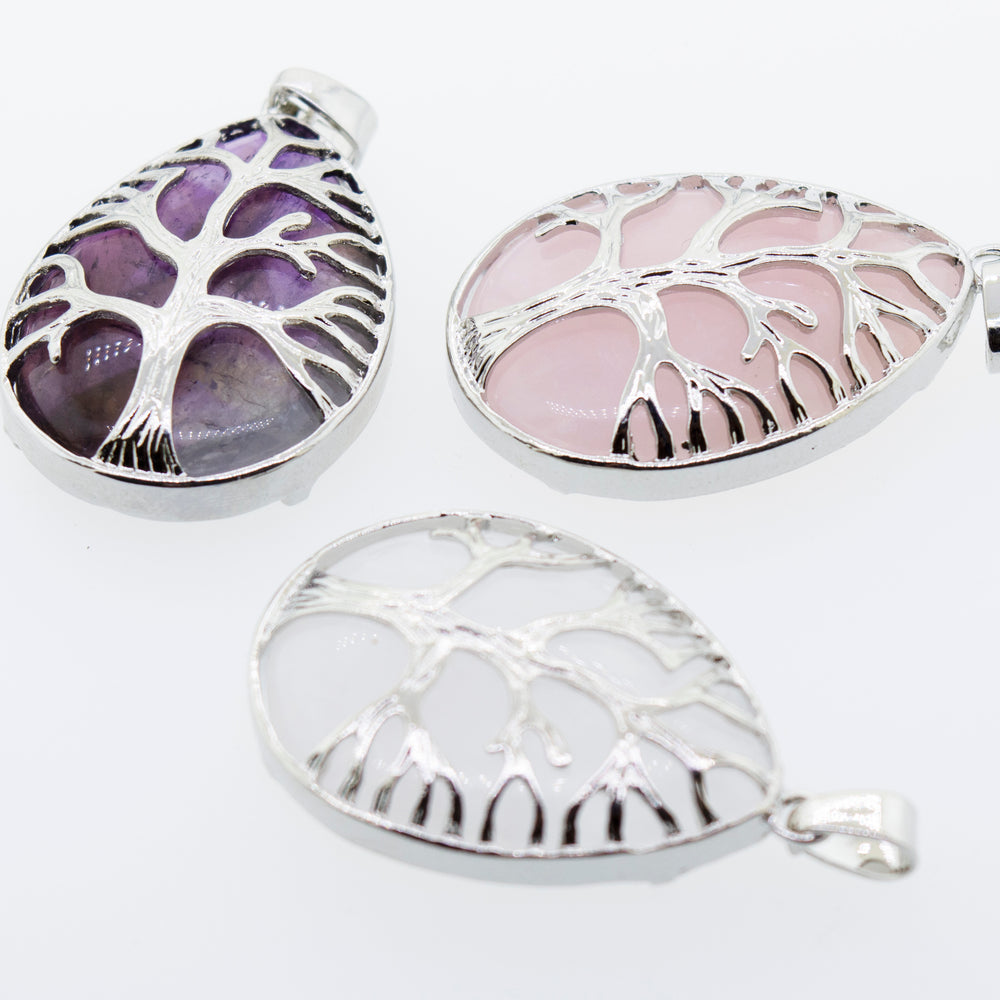 
                  
                    Three Super Silver Teardrop Shape Stone with Silver Plated Tree Of Life Pendants featuring a Rose Quartz stone, on a white surface.
                  
                