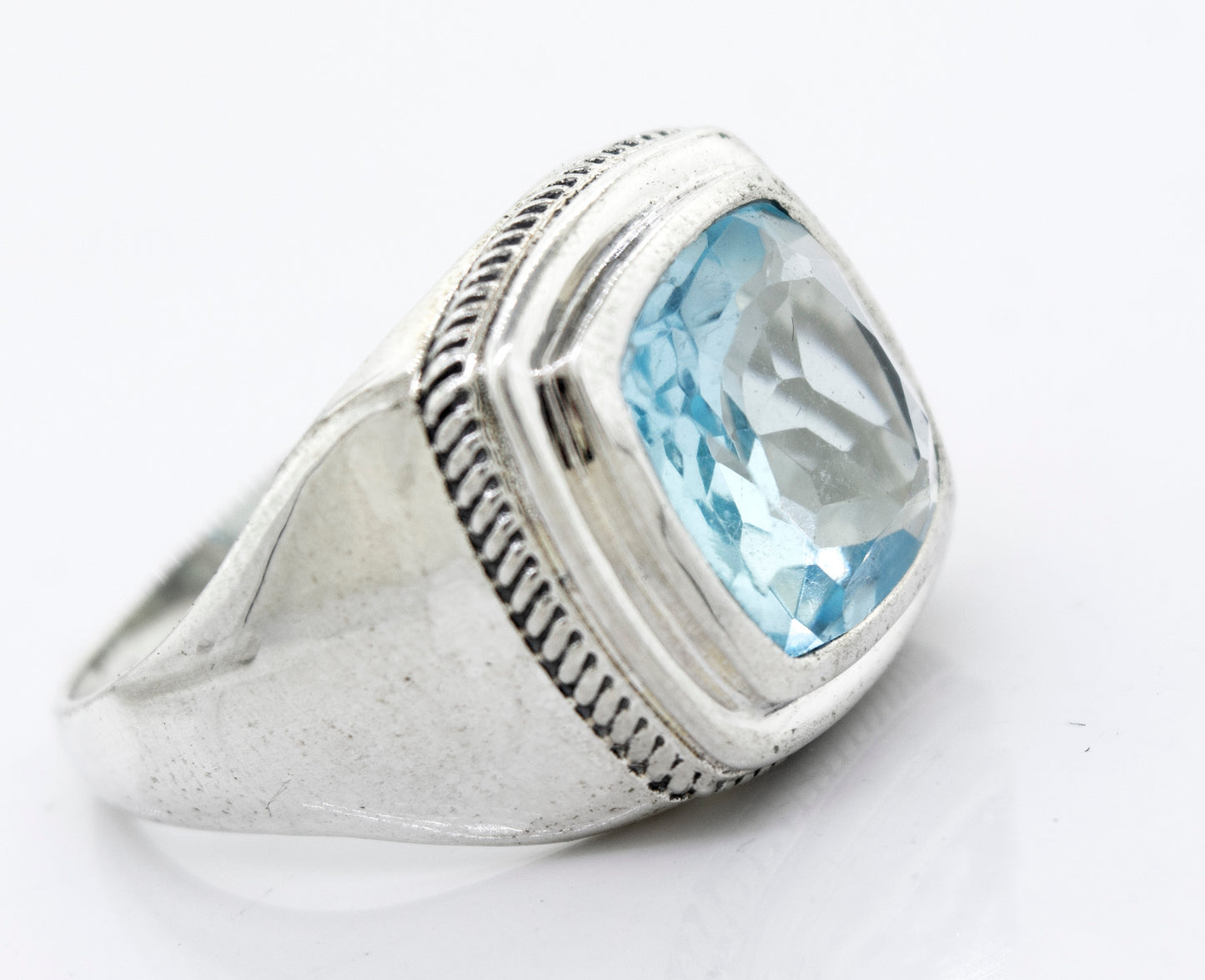 
                  
                    A Faceted Stone Signet Ring with a rectangular blue topaz gemstone set in a faceted cut on a white background.
                  
                